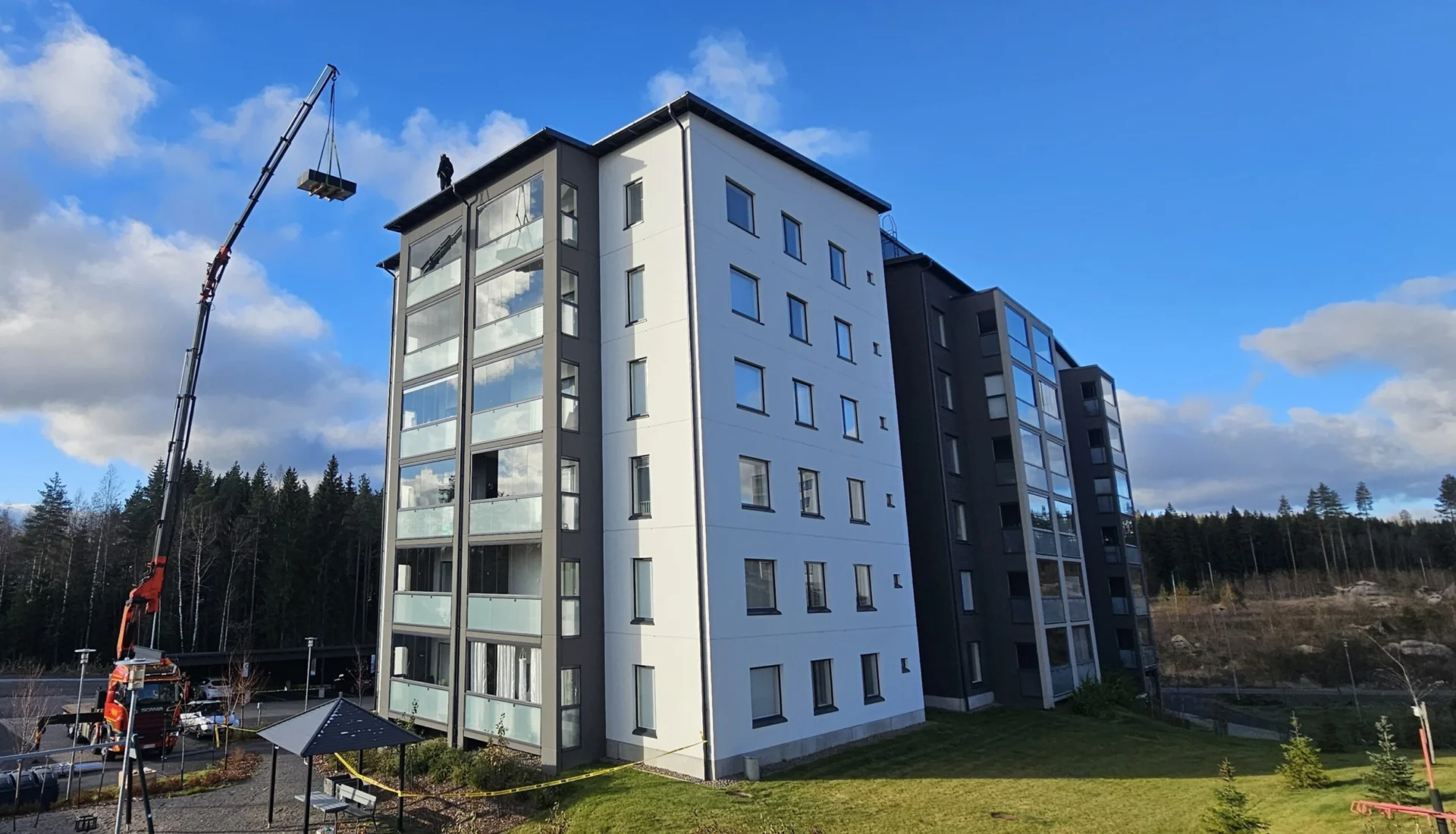 Aurinkopaneeleja nostetaan nosturilla kerrostalon katolle